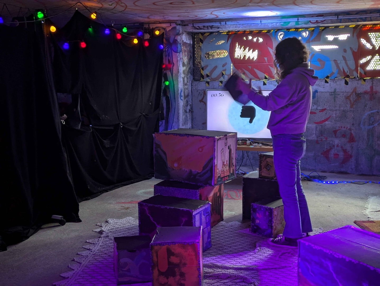 Photographie d'une personne avec un cube en main, entourée de cubes de différentes tailles avec des illustrations sur chaque face